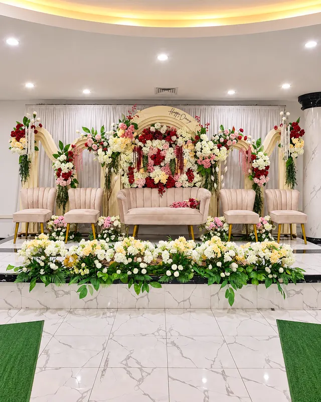 Pelaminan dengan backdrop bunga dan sofa krem