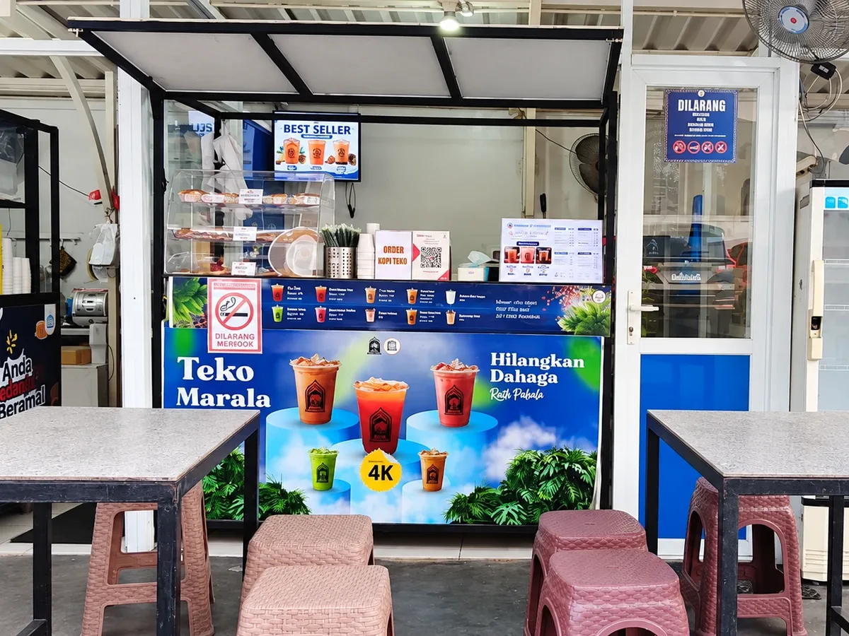 Gerai Teko Marala dengan etalase roti, layar menu, dan meja kursi di depannya